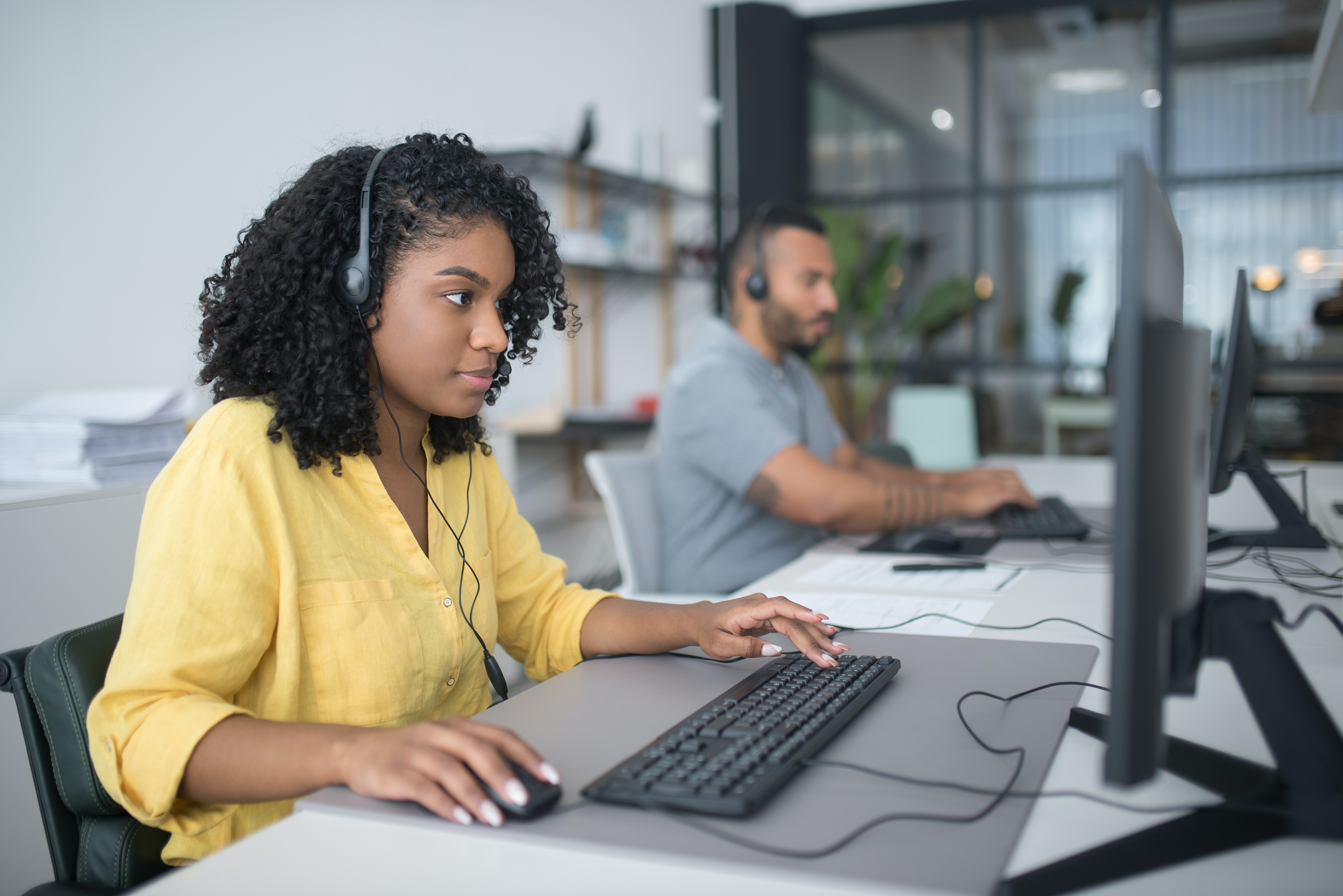 black female customer service person looking at a computer and wearing a headset